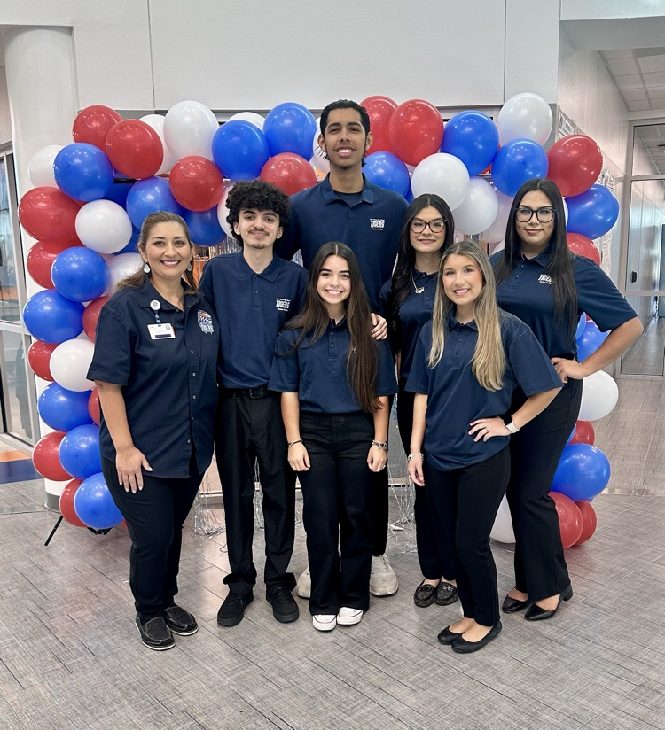 Alt text: Carroll High School students smile and wave small American flags during the Veterans Day 