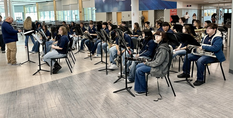 Alt text: Carroll High School students smile and wave small American flags during the Veterans Day 