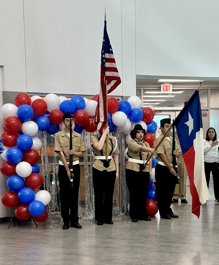 Alt text: Carroll High School students smile and wave small American flags during the Veterans Day 