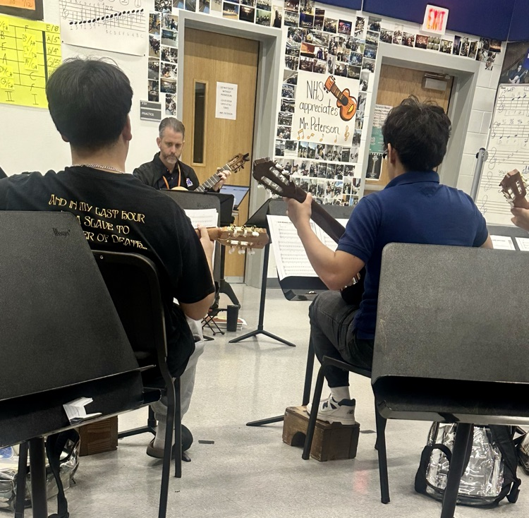 Students in advanced guitar class practicing together with guitars and music stands for the upcoming Winter Holiday Concert.