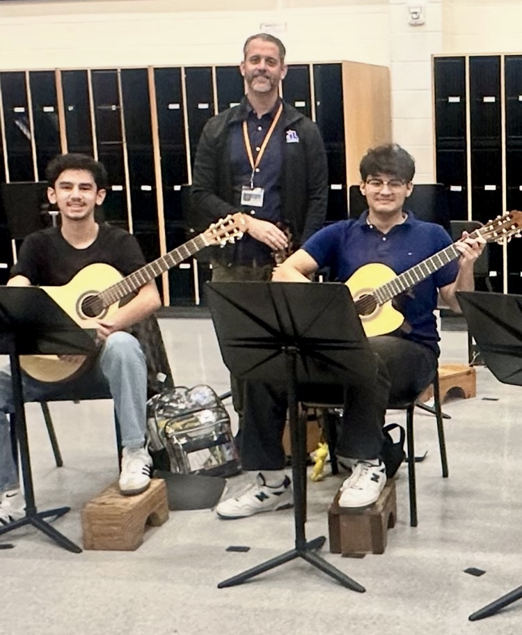 Students in advanced guitar class practicing together with guitars and music stands for the upcoming Winter Holiday Concert.