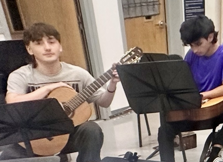 Students in advanced guitar class practicing together with guitars and music stands for the upcoming Winter Holiday Concert.