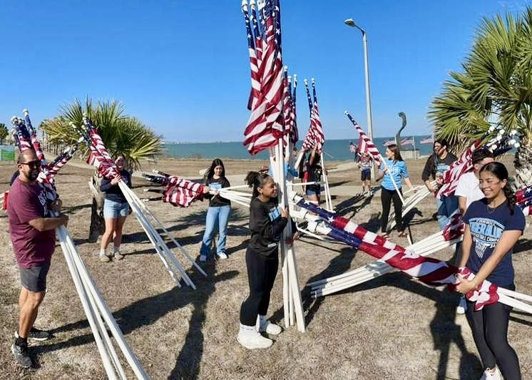 Students from Carroll’s girls basketball team help remove American flags from the Flags for Heroes display by the bay.