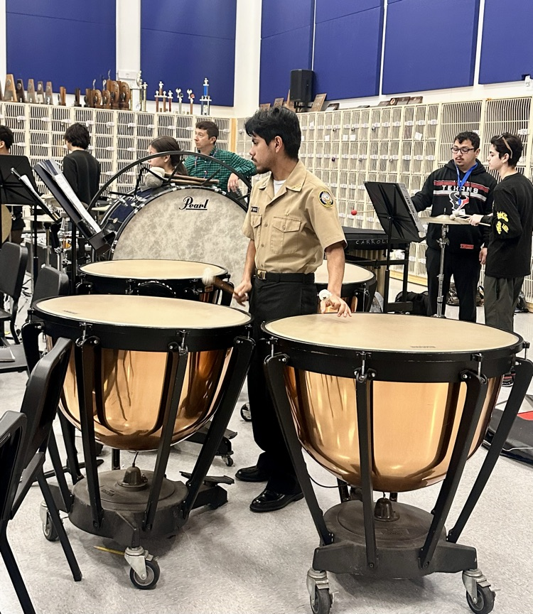 Alt text: Students in band rehearsal playing flutes, brass instruments, and timpani drums while preparing for a holiday concert.