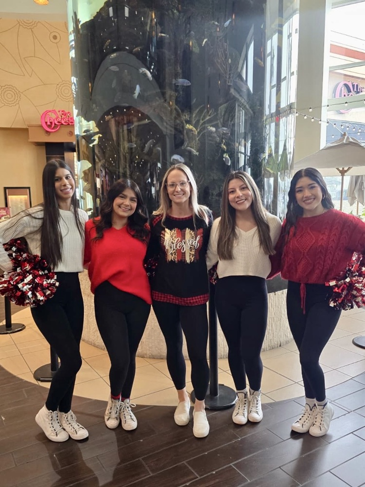 Five Tigerette Officers stand together inside La Palmera Mall wearing festive sweaters and black leggings
