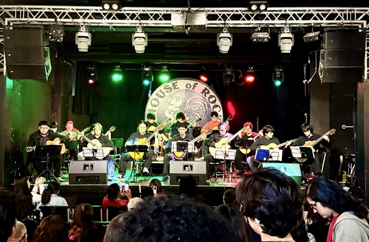 A stage full of CCISD high school guitar students performing under red and green spotlights at House of Rock.
