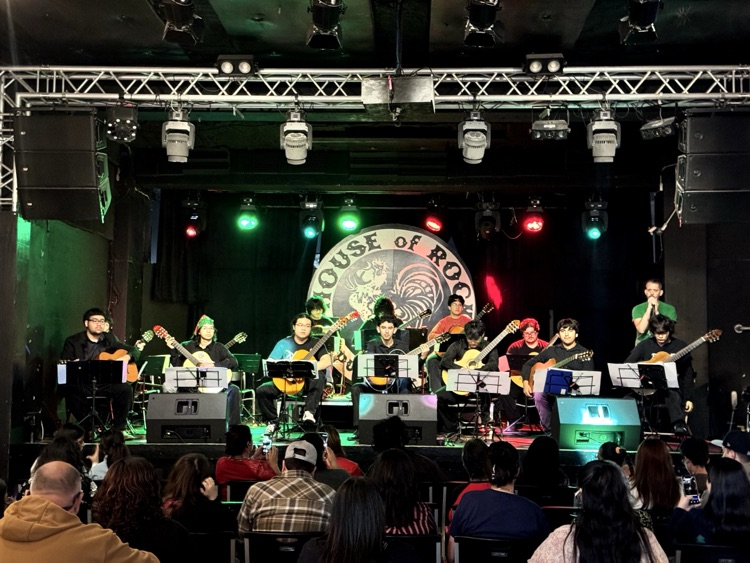 A stage full of CCISD high school guitar students performing under red and green spotlights at House of Rock.