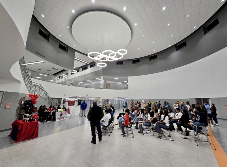 ⸻ Alt Text: Talina Valdez sits at a signing table with her family during her college softball signing ceremony. Trinity Valley Community College
