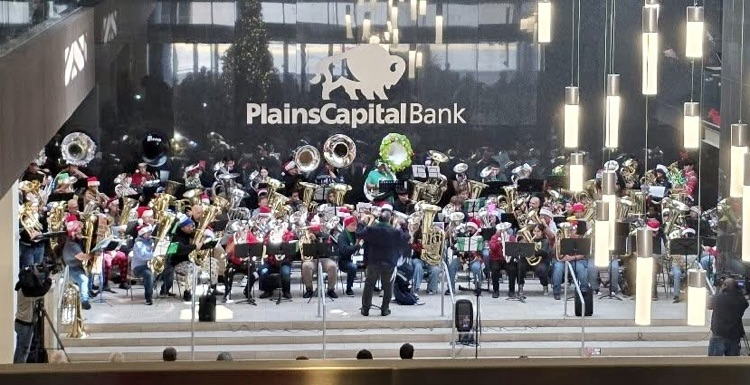 Carroll tuba students performing with a large group of tubists during a holiday Tuba Christmas concert indoors.