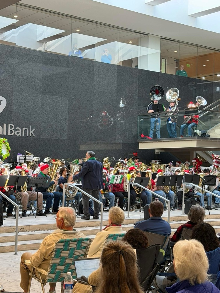 Carroll tuba students performing with a large group of tubists during a holiday Tuba Christmas concert indoors.