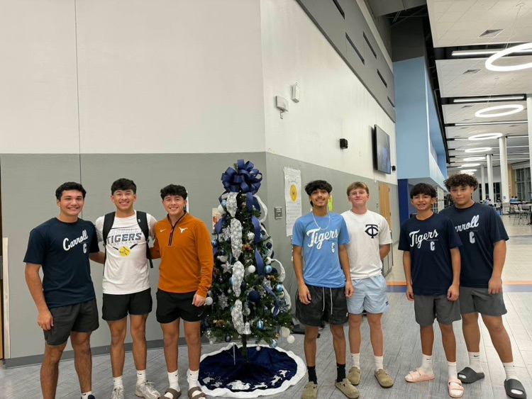 Carroll Tigers baseball players decorate a blue-and-white Christmas tree inside the school