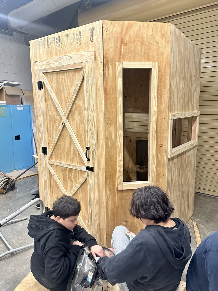 Construction students working on a wooden structure in a workshop.