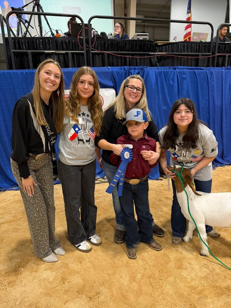 Carroll FFA students stand with a young exhibitor holding a ribbon during the NCJLS All-Star Show.