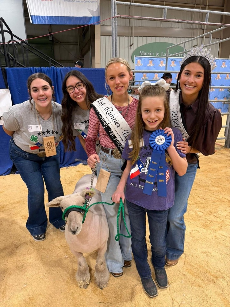 Carroll FFA students stand with a young exhibitor holding a ribbon during the NCJLS All-Star Show.
