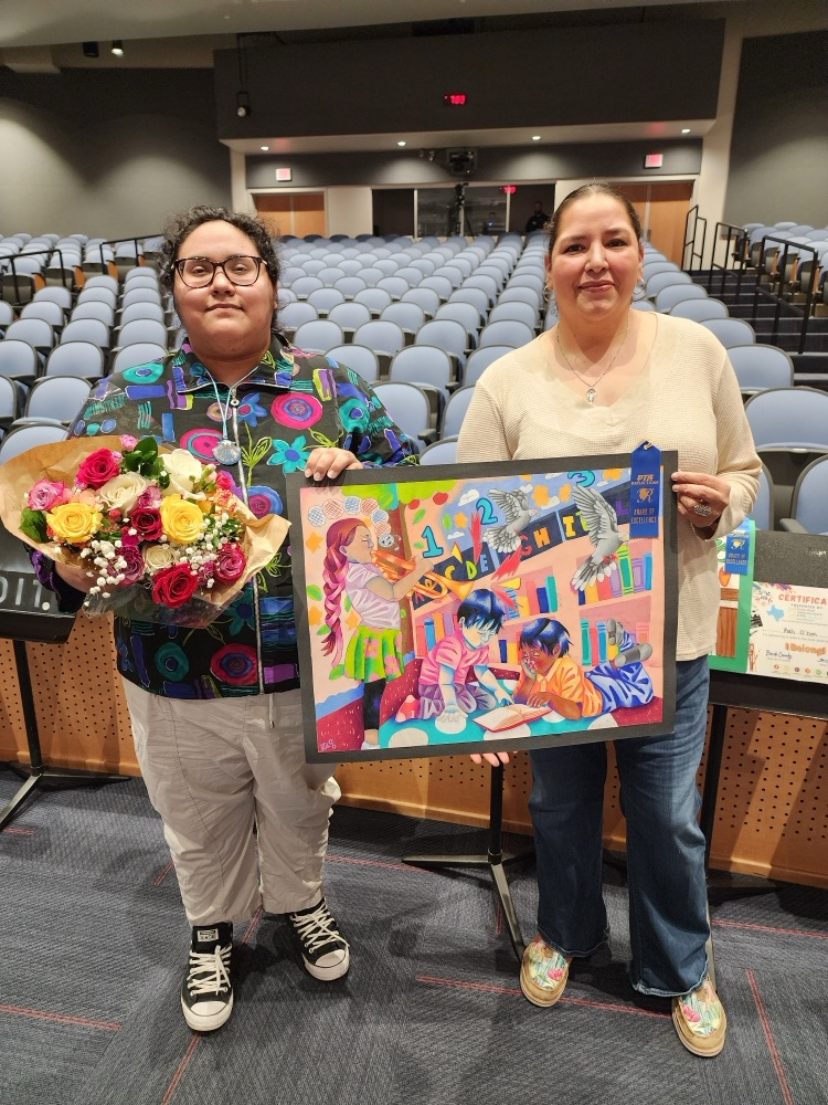 Student holds a colorful award-winning artwork alongside family members in an auditorium, celebrating advancement to the state PTA Reflections contest.