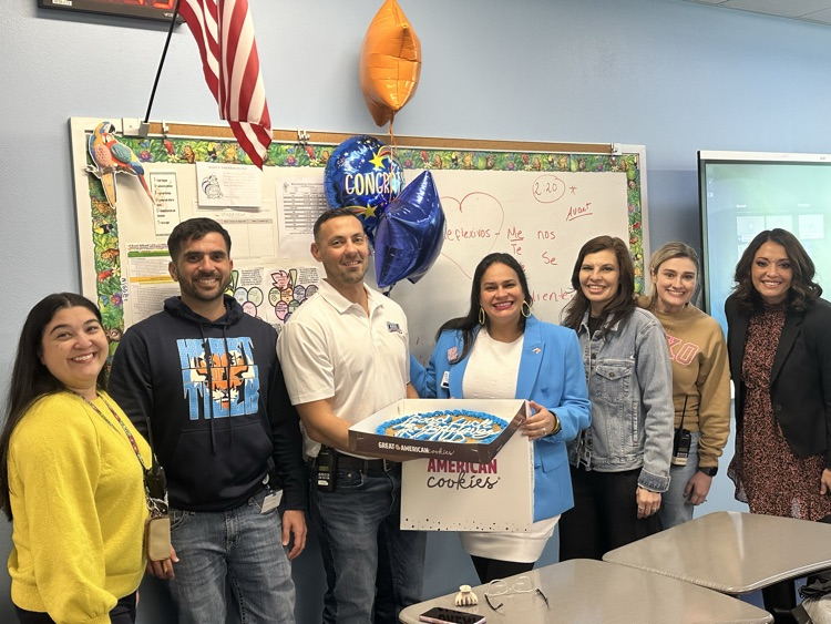 Staff celebrating Señora Rodriguez with balloons and a cookie cake in her classroom. 🎉🍪💙