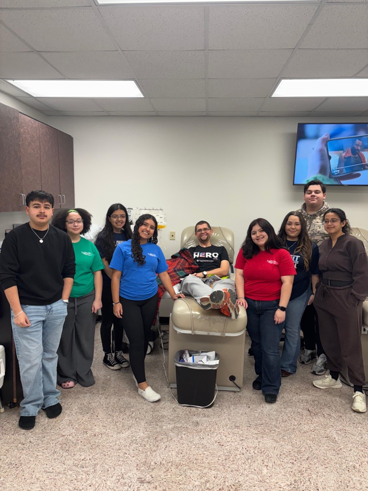 Carroll HOSA students pose with their advisor while he donates blood at a blood center, showing teamwork, service, and school pride.
