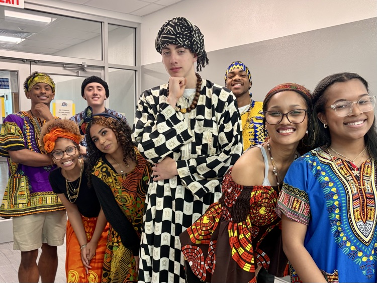 Students from the African American Culture Club modeling colorful traditional attire during a Black History Month fashion show celebration.