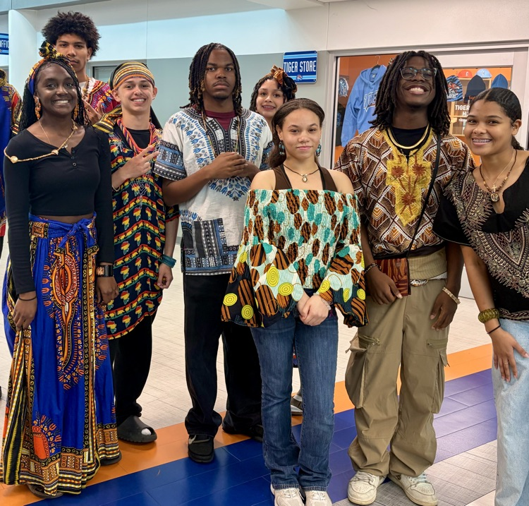 Students from the African American Culture Club modeling colorful traditional attire during a Black History Month fashion show celebration.