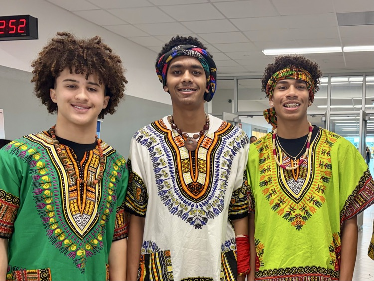Students from the African American Culture Club modeling colorful traditional attire during a Black History Month fashion show celebration.