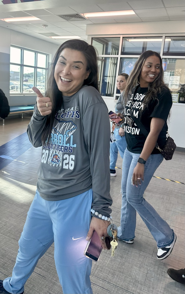 ⸻ Short alt text: Smiling coach gives a thumbs up in the hallway celebrating a Round 2 playoff win.