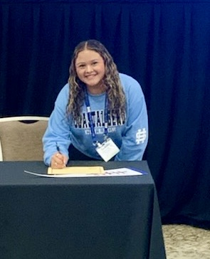 TAFE students sign college commitments as education majors at the state competition in Dallas, holding certificates and college pennants.