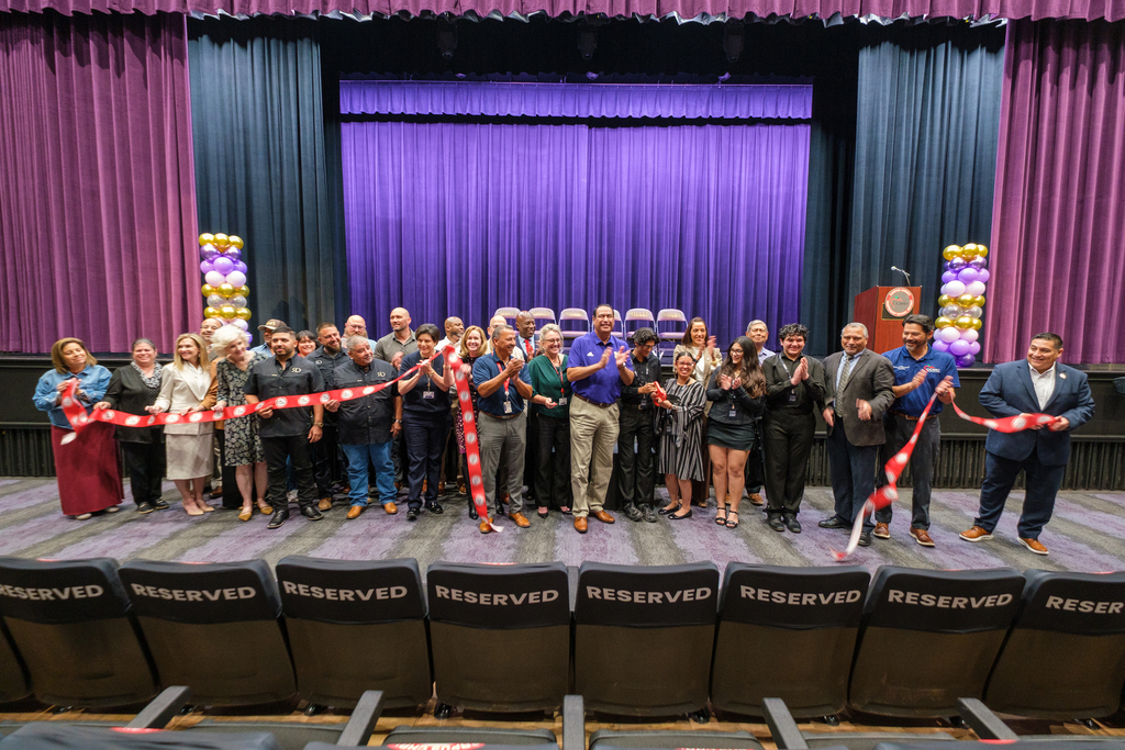 A group of people celebrating after cutting a ribbon at a ribbon cutting ceremony. 