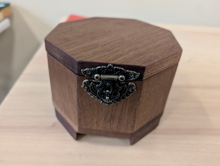 Alt text: Handcrafted wooden box with metal latch on display 