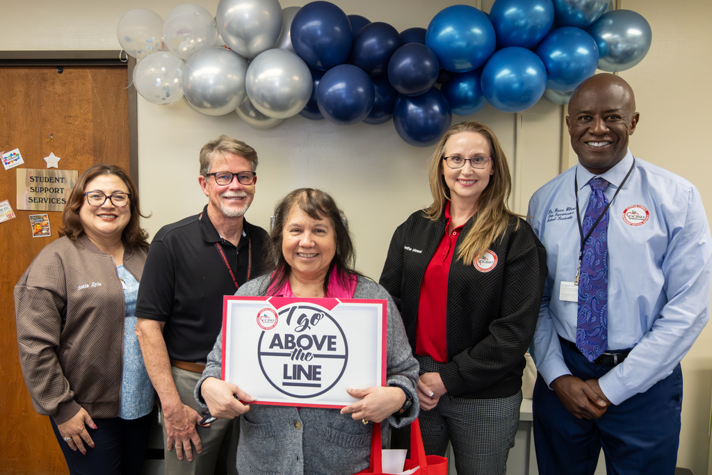 Brenda J. Rodriguez, Above the Line winner, holds up a poster as she poses for a photo with district administration. 