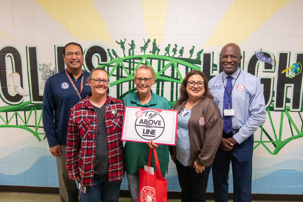 Joanna Spinney, Above the Line winner, holds up a poster as she poses for a photo with district administration. 