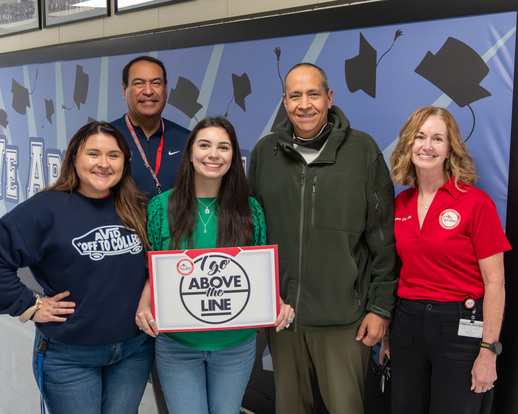 Isabella Ramirez, Above the Line winner, holds up a poster as she poses for a photo with district administration. 