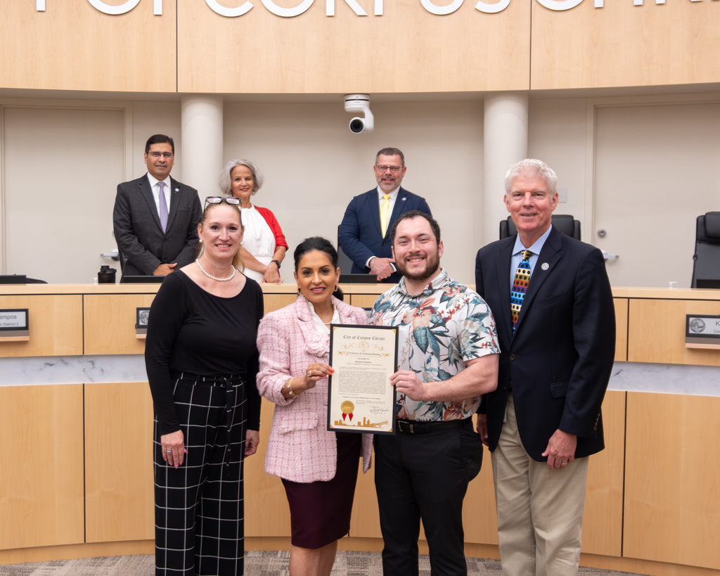 Samuel Zamora poses for a photo with Corpus Christi City Council Reps during a meeting.