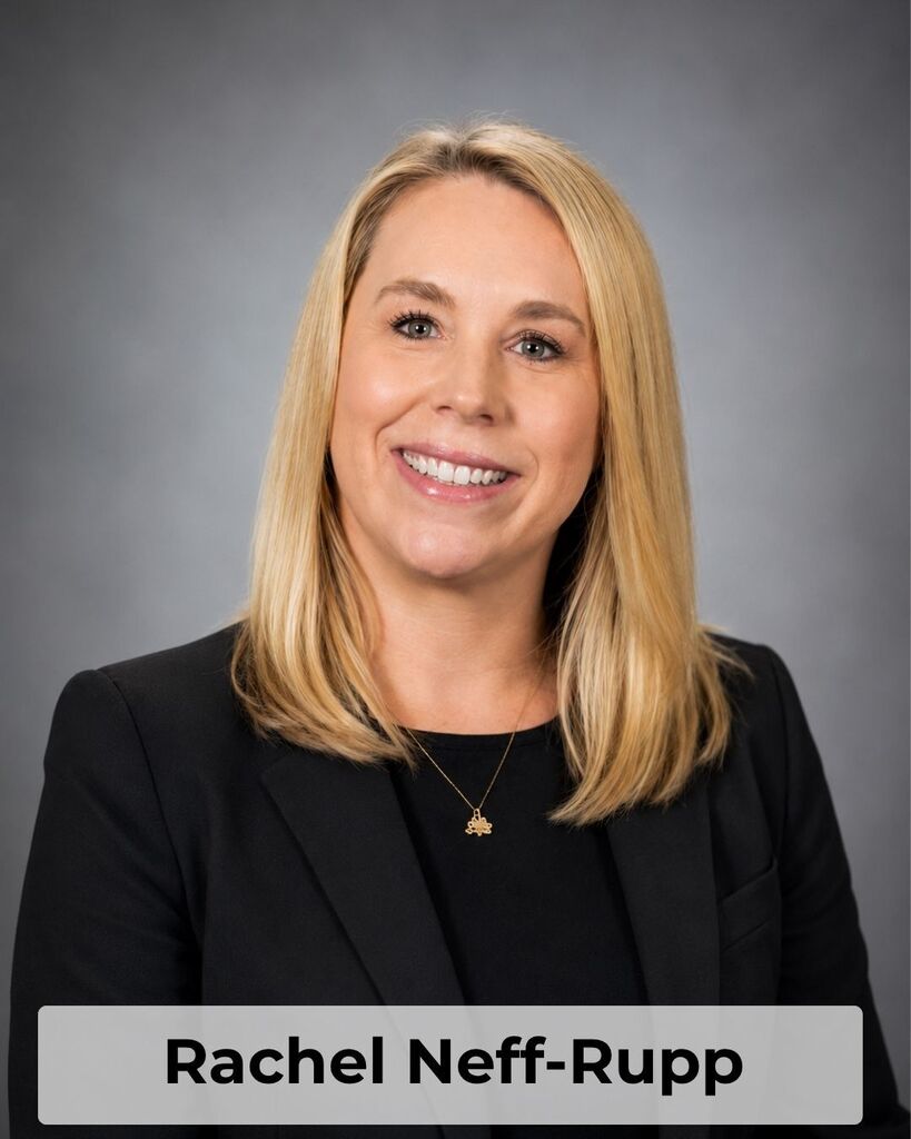 A woman with blonde hair, wearing a black blazer, a necklace, and smiling for a photo. Name: Rachel Neff-Rupp.