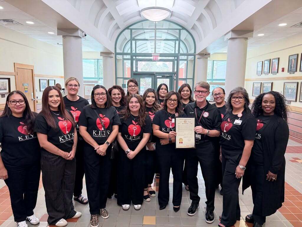 A group of people in matching black t-shirts pose for a picture with an award.