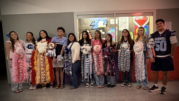 A group of students wearing pink and white outfits, standing in a line, posing for a photo.