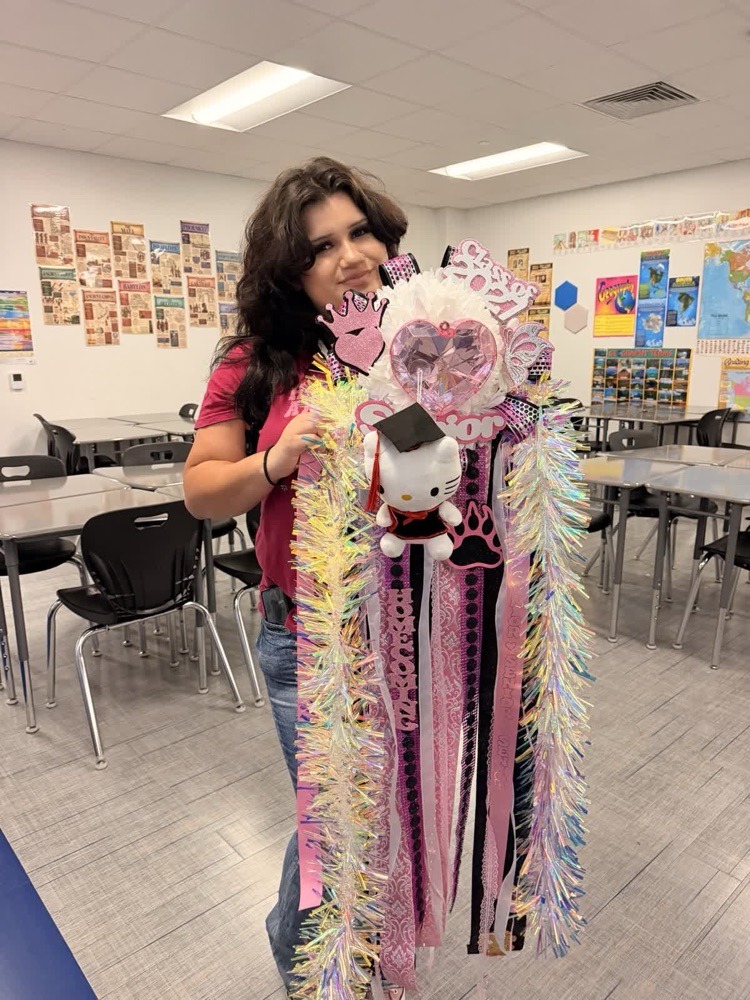 A woman holds a large tassel with a graduation cap, ribbons, and a Hello Kitty plush toy.