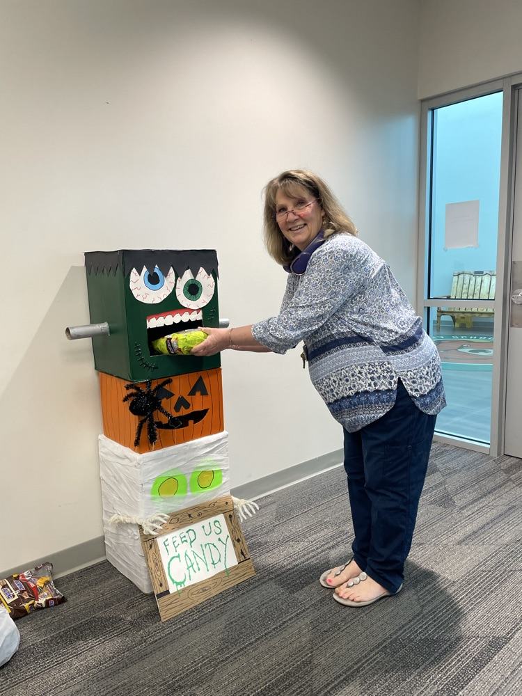 Woman throwing a ball into a box with a monster face on top of it.