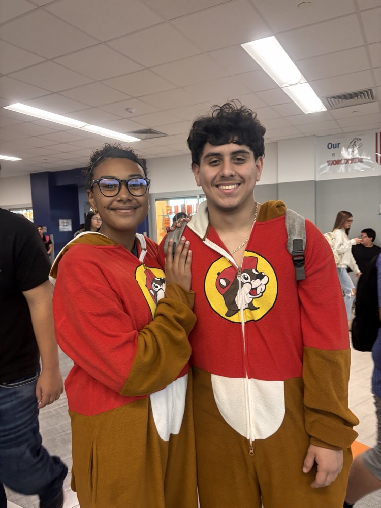 Two students in matching red and brown costumes pose for a photo in a hallway.