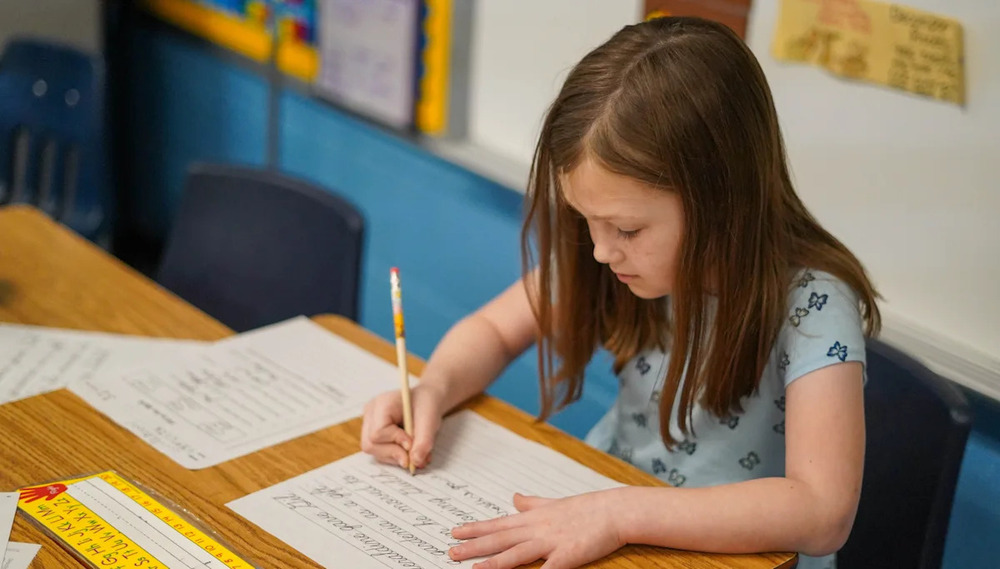 student writing cursive in the classroom