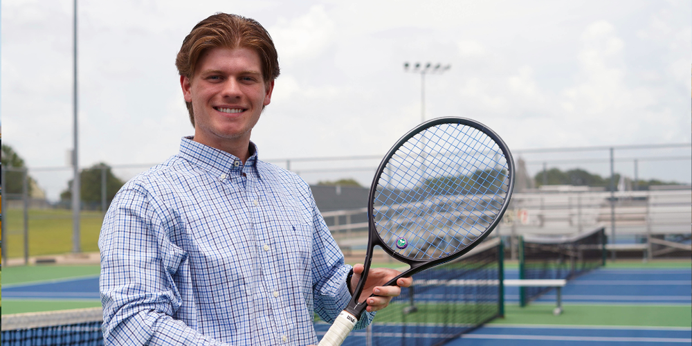 well dressed man holds tennis racket