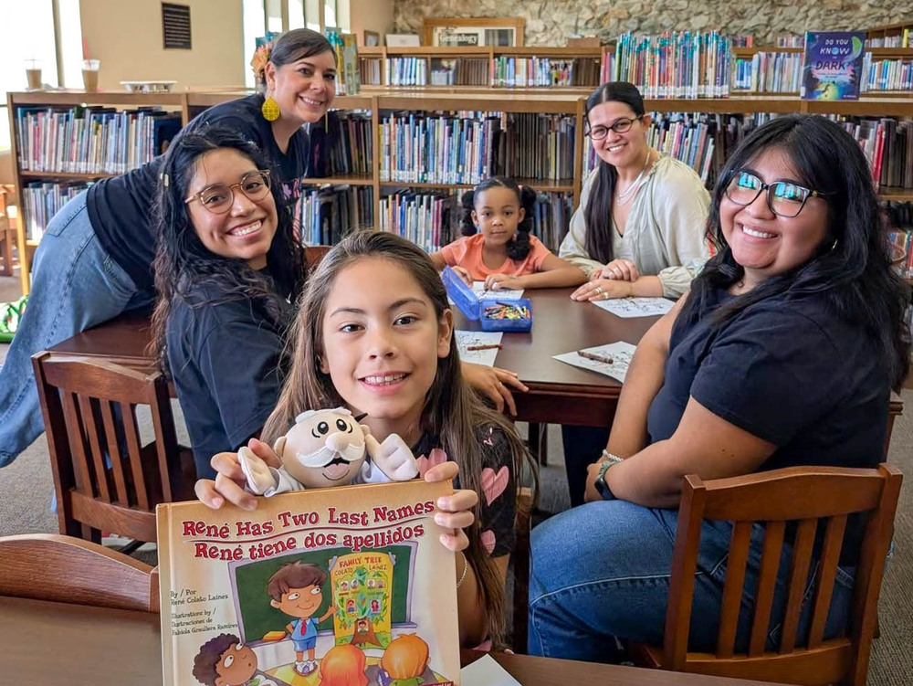 Corsicana ISD teacher gathered around a table in a library during a bilingual reading activity