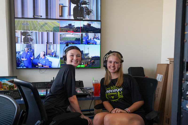Control room atop Community National Bank & Trust Stadium buzzes with activity as crews run cables, cue graphics, and check audio.