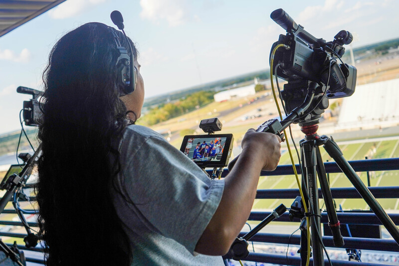 Control room atop Community National Bank & Trust Stadium buzzes with activity as crews run cables, cue graphics, and check audio.