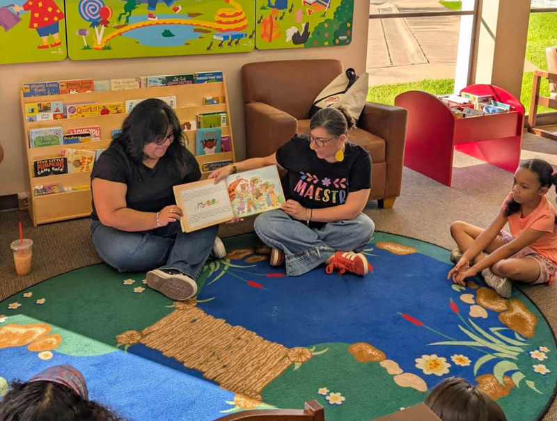 Corsicana ISD teacher gathered around a table in a library during a bilingual reading activity