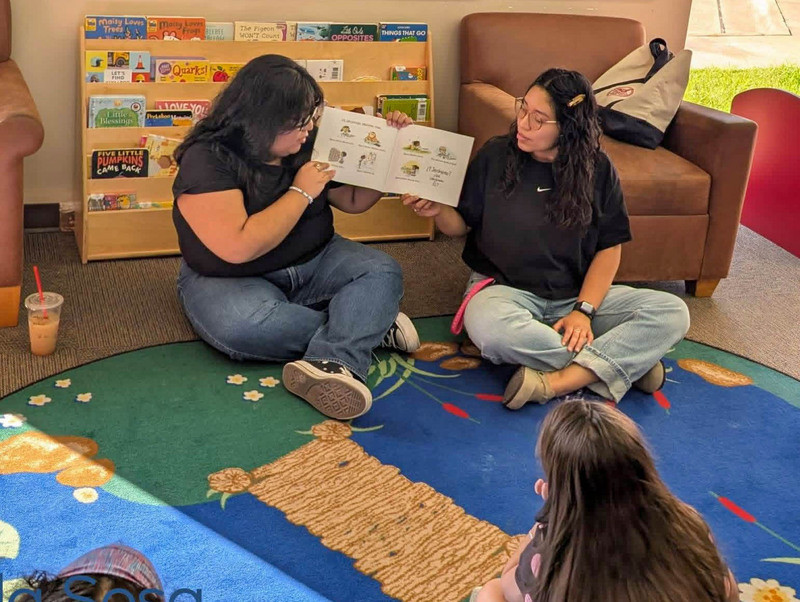 Corsicana ISD teacher gathered around a table in a library during a bilingual reading activity