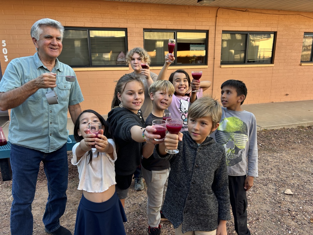 Mr. Lansing and 7 students with raised glasses toward the camera enjoying their prickly pear juice