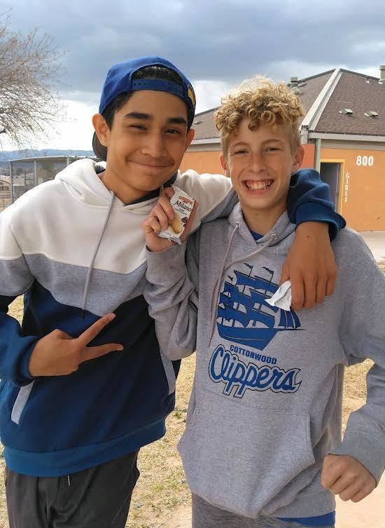 Two smiling male students holding up package of almonds