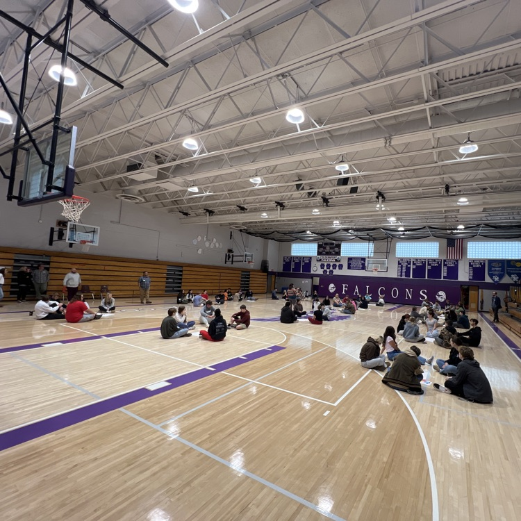 students sitting in groups on the gym floor.