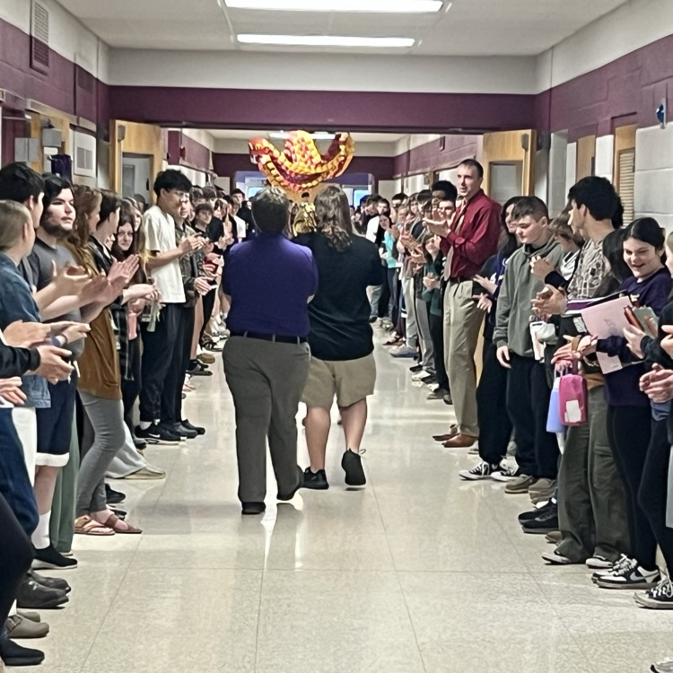 Ty and Mr. Ouellette walking in the hallway as students line the halls clapping.