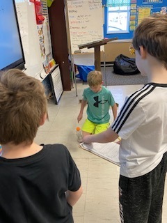 Fourth Grade: Liam, Otto, and Jayce mastering the bottle flip activity in math class! 